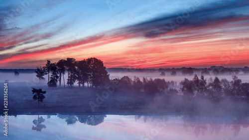 Tranquil wet land at a colorful daybreak with dramatic clouds, Turnhout, Belgium