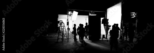 Silhouette images of video production behind the scenes or b-roll or making of TV commercial movie that film crew team lightman and cameraman working together with director in big studio © gnepphoto
