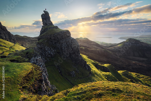Person standing on top of mountain against cloudy sky during sunset