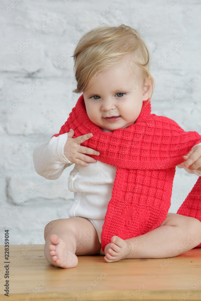Indoor portrait of a cute blond baby wearing a red wool shawl Indoor portrait of a cute blond baby wearing a red wool shawl