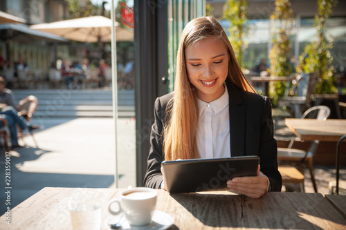Beautiful business woman work on tablet in a bar and drink coffee