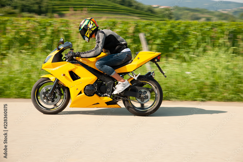 Man drive a motorbike on a country road with vineyards in background
