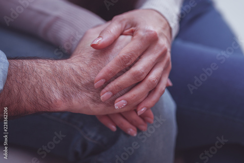 Romantic feelings. Close up of lovely couple sitting together while holding tenderly by hands and enjoying being with each other