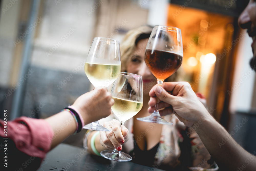 Group of friend toast with red and white wine. Main focus on one of the glasses, blurred background