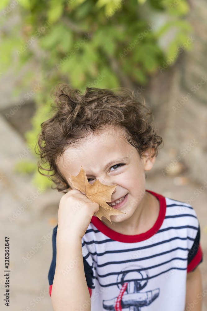 Fototapeta premium Child playing with an autumn fall leaf