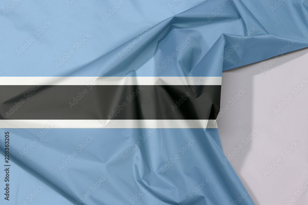 Botswana fabric flag crepe and crease with white space, black stripe with a  thin white frame on light blue. Stock Photo | Adobe Stock