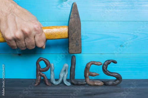 Breaking the rules concept, plasticine letters and a hammer on the blue background. photo