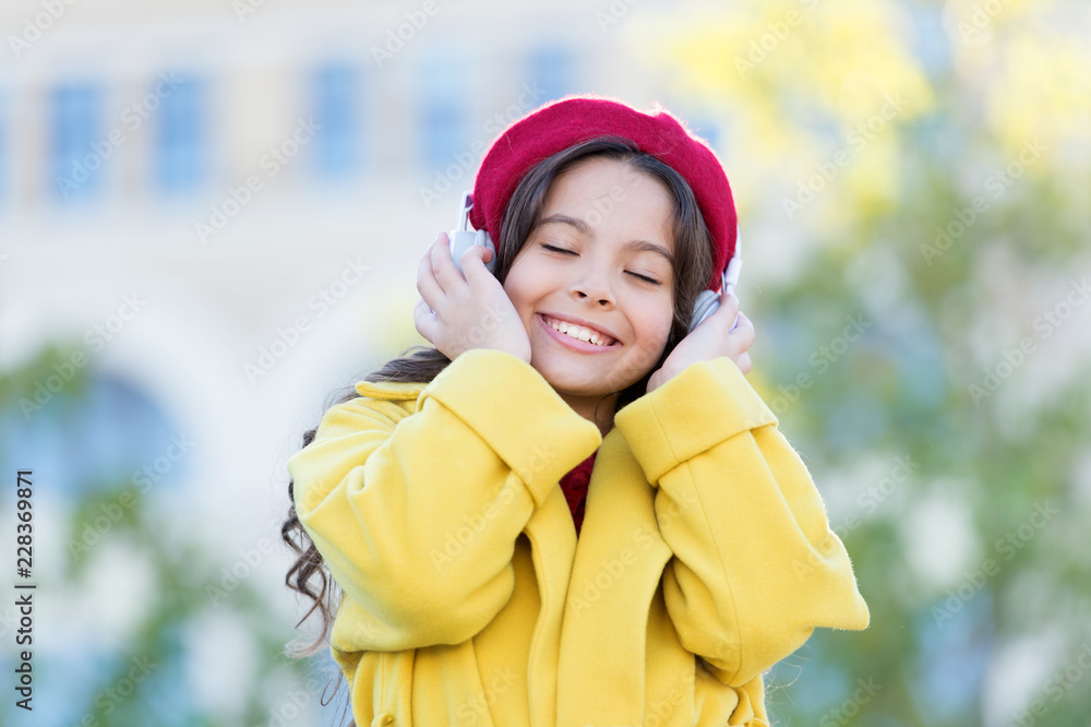 Girl with headphones urban background. Positive influence of music. Child girl french style outfit enjoying music. Childhood and teenage music taste. Little girl listening music enjoy favorite song