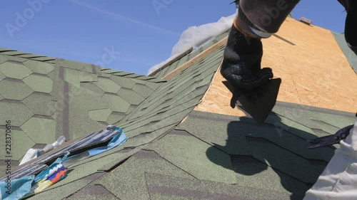 soft roof of shingles. Repair of the roof of a residential house. installation of soft tiles. partial replacement of the damaged roof. Dot repair. master cuts off excess roofing material with scissors