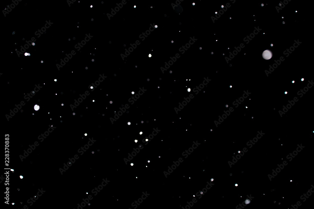 Snowstorm texture. Bokeh lights on black background, shot of flying snowflakes in the air Snowstorm texture. Bokeh lights on black background, shot of flying snowflakes in the air