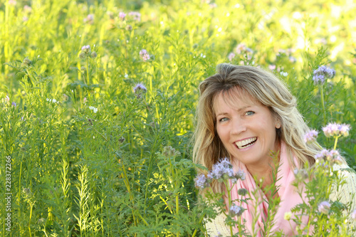 Happy mature woman in a green flowerfield