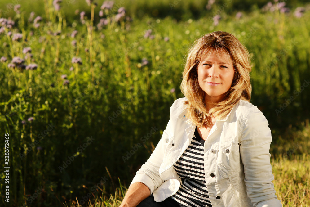 Portrait of a smiling middle age woman relxing in the meadow Portrait of a smiling middle age woman relxing in the meadow