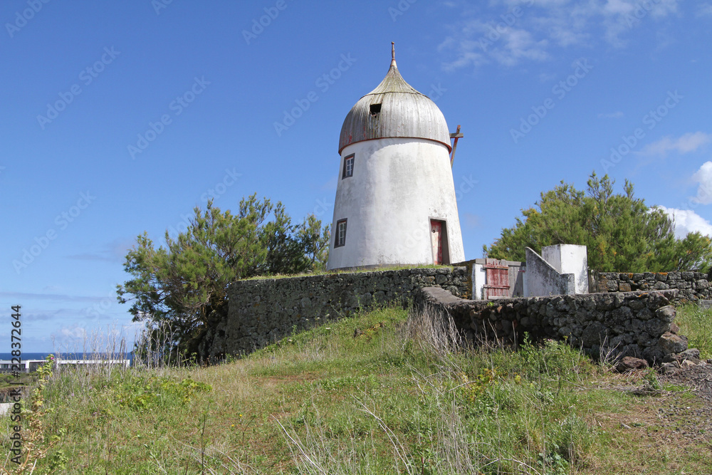 historic windmill with traditional wooden pointed done sitting on rock foundation, Graciosa Island, Azores, Portugal