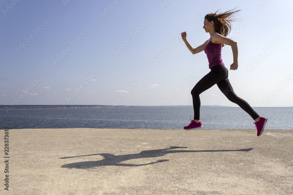 Young beautiful girl jogging and training on the beach