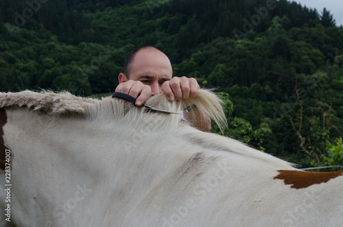 Man cutting horsehair to a horse.