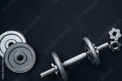 metal weights and dumbbells with discs, for sports on black background
