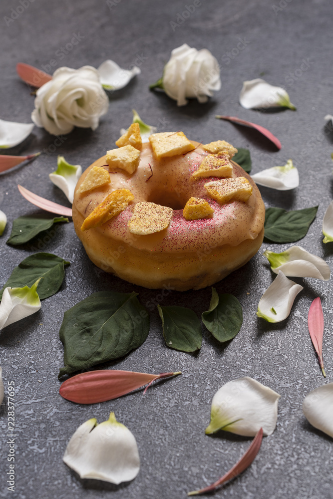 American doughnut with spring flowers petals on the wooden table. American doughnut with spring flowers petals on the wooden table.