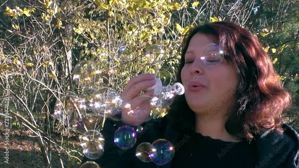 Woman blowing bubbles in the park. Slow motion. Close-up. Woman blowing bubbles in the park. Slow motion. Close-up.