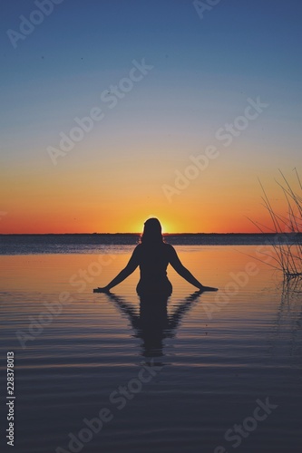 Woman in the sea while the sun sets © Jan