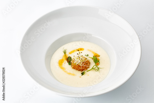 cream soup with greens in a large white plate isolated on white background