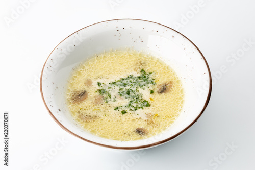 cream soup with greens in a large white plate isolated on white background