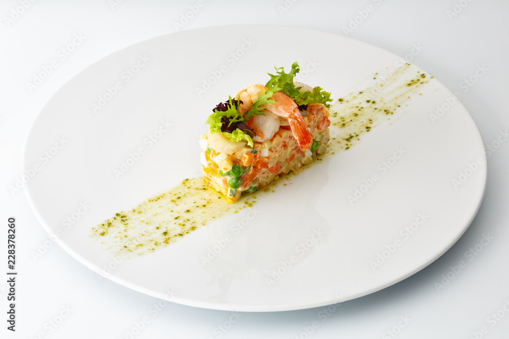 Russian salad with shrimp in a creamy sauce in a white plate, isolated on white background Russian salad with shrimp in a creamy sauce in a white plate, isolated on white background