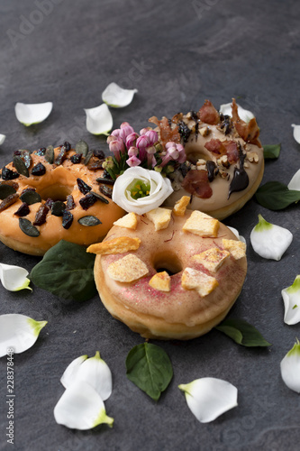 Foto Set of three American unusual doughnuts decorated with flower leaves