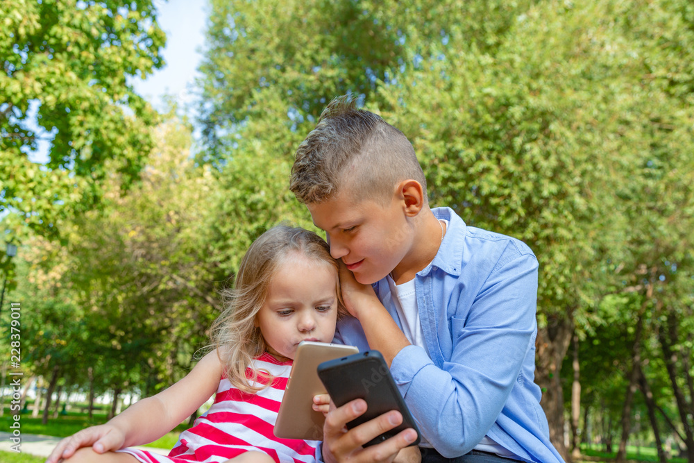 busy kids looking at their phones texting sms and playing sitting outside busy kids looking at their phones texting sms and playing sitting outside