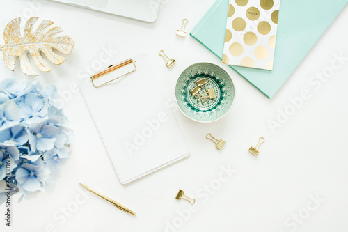 Home office desk workspace with blank paper clipboard, hydrangea flower bouquet on white background. Flat lay, top view mock up. photo