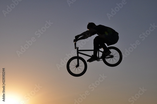 silhouette of cyclist on a white background of blue sky