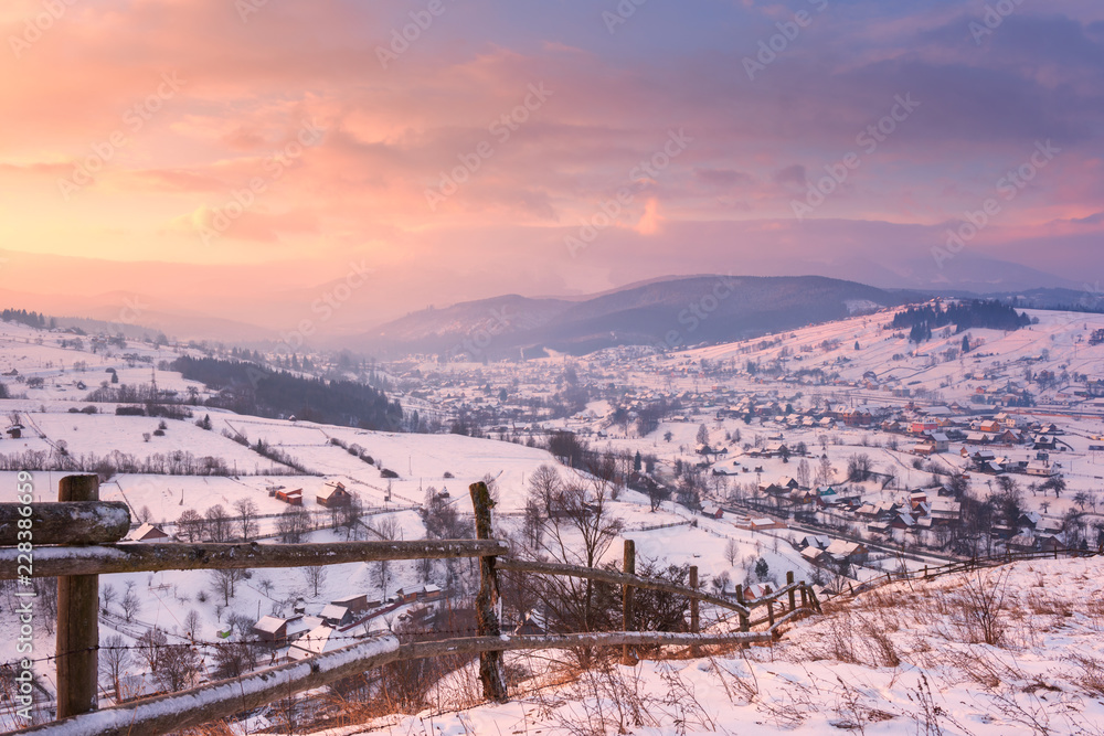 Beautiful winter landscape in soft sunset light, alpine valley surrounded by wooded mountains, Carpathians