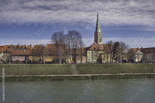 River Savinja and old houses with parish church of Saint Daniel in Celje, Slovenia