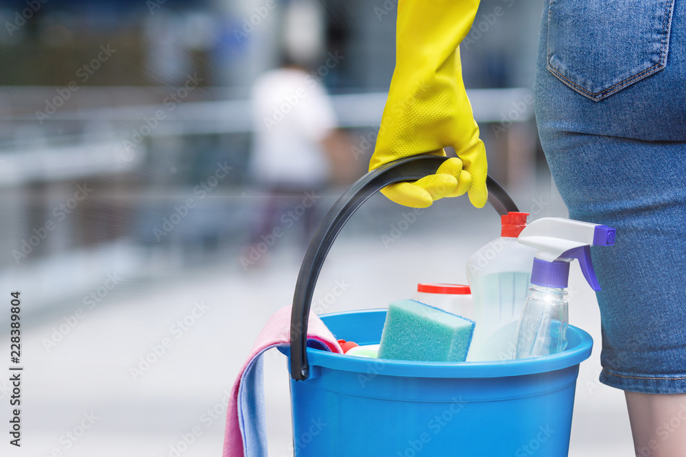 A woman carrying a bucket fulfiled with the chemical staff in her hand in rubber glove. A woman carrying a bucket fulfiled with the chemical staff in her hand in rubber glove.
