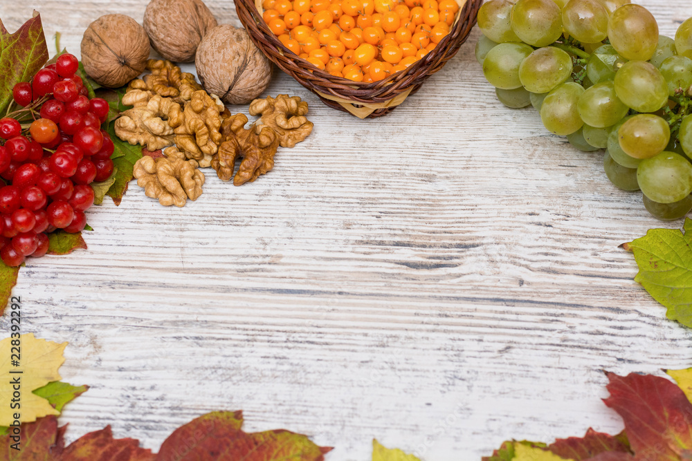Vitamins of autumn. Viburnum, sea buckthorn, grapes, close-up on a light textured wooden background. Copy space Vitamins of autumn. Viburnum, sea buckthorn, grapes, close-up on a light textured wooden background. Copy space
