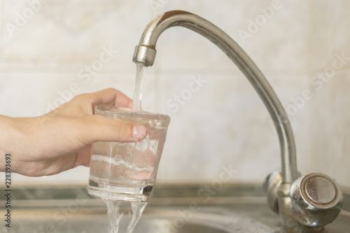 close up hand holding glass fill with water pour from tap d