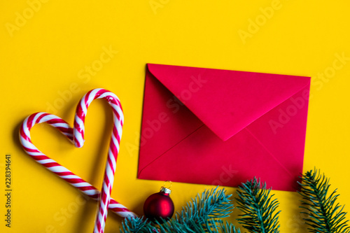 Red christmas envelope and lolipops on yellow background photo