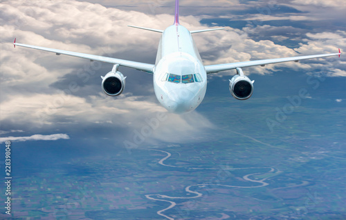 An airplane is flying over low clouds with blue sky - Airplane taking off from the airport - Travel by air transport