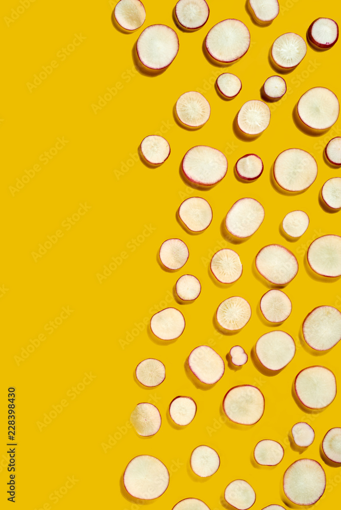 Spring organic healthy vegetables - slices of radish in a creative pattern on a yellow background. Flat lay. Spring organic healthy vegetables - slices of radish in a creative pattern on a yellow background. Flat lay.