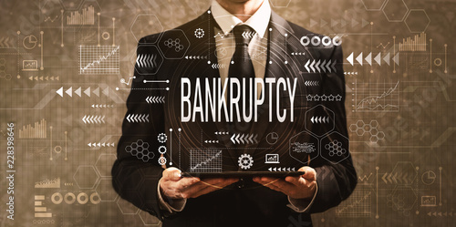 Bankruptcy with businessman holding a tablet computer on a dark vintage background photo