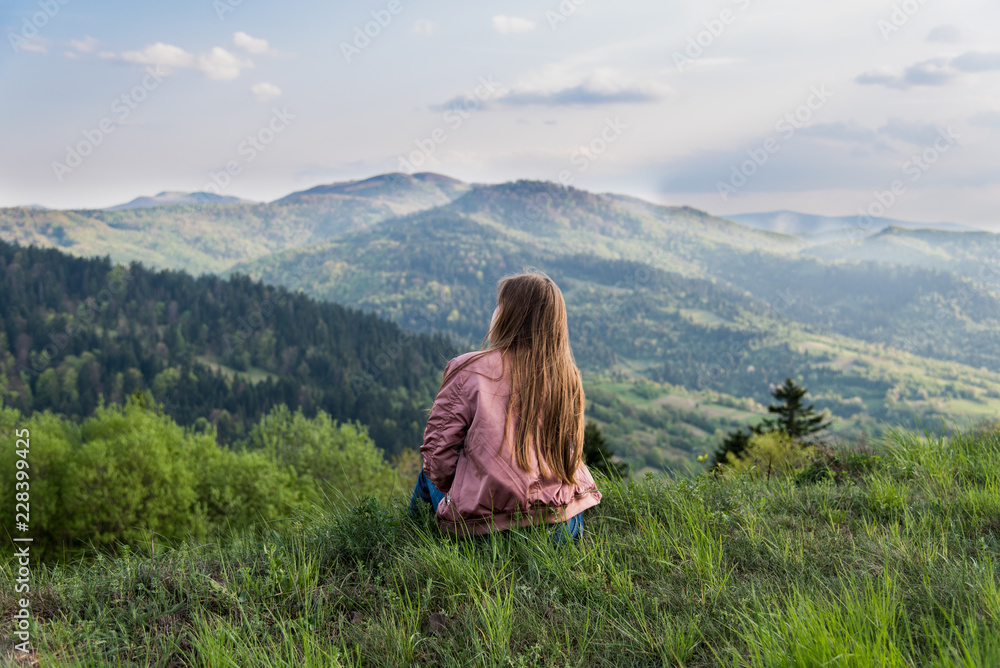 Beautiful girl rests at the precipice the top of mountains, hiking enjoying moment, nature, traveling tourism. The Carpathians mountains. Cute tenage girl. Lifstyle concept.