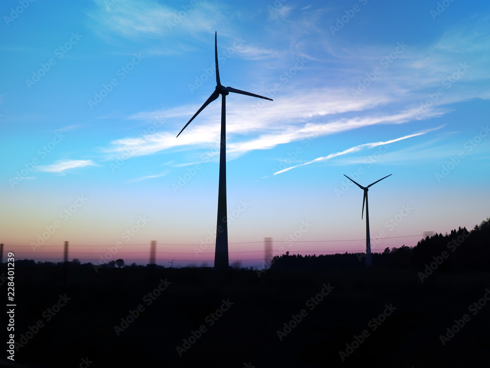 Wind mills during dusk. Silhouettes of the machines rotating in the morning.