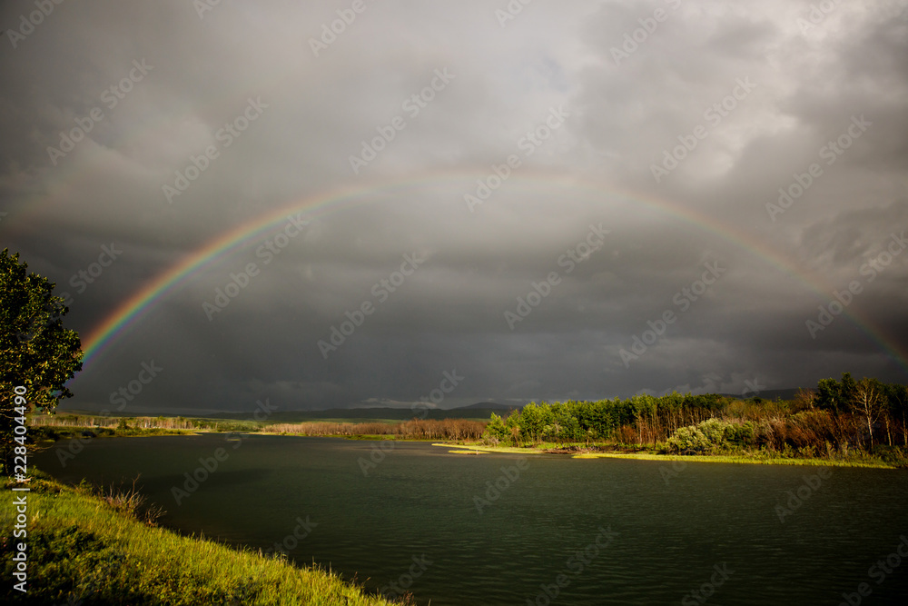 Stormcloud rainbow over river Stormcloud rainbow over river