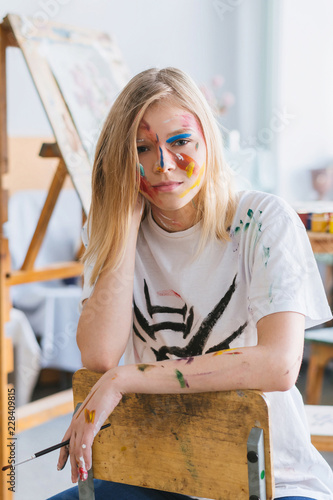 A young attrective artist girl with a face and clothes in the paint. photo