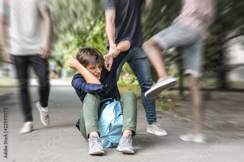 Aggressive teenagers bullying boy outdoors, view with motion blur effect photo