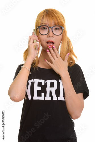 Young cute Asian nerd woman talking on mobile phone looking shoc photo