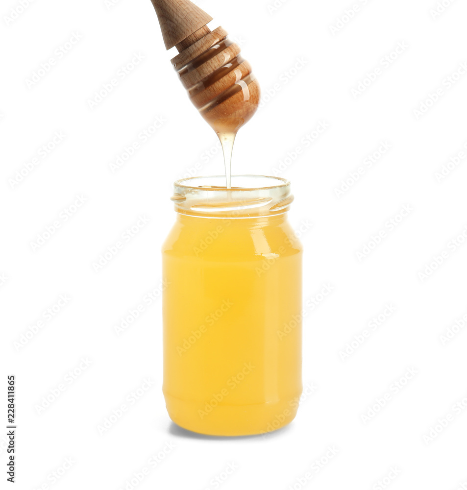 Honey dripping from dipper into jar on white background Honey dripping from dipper into jar on white background