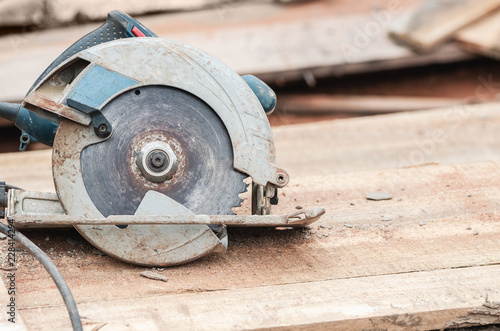 Circular saw over a pile of wooden planks.