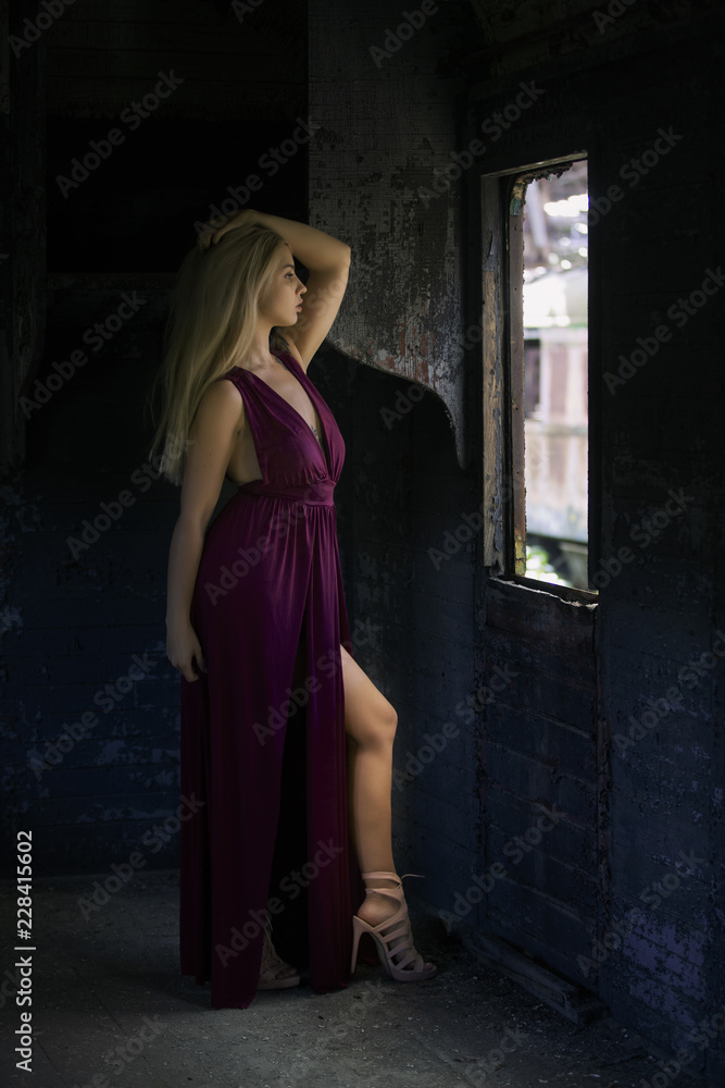 Fashion woman posing in the train wagon at the window in abandoned Red Star graveyard