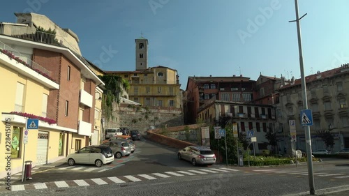 Traffic passes in front of Via Riva in Ivrea, Italy as a car climbs the steep and winding hill in the morning sunlight photo