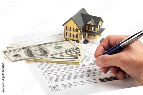 Hand Signing a Lease Agreement Document with Model House and